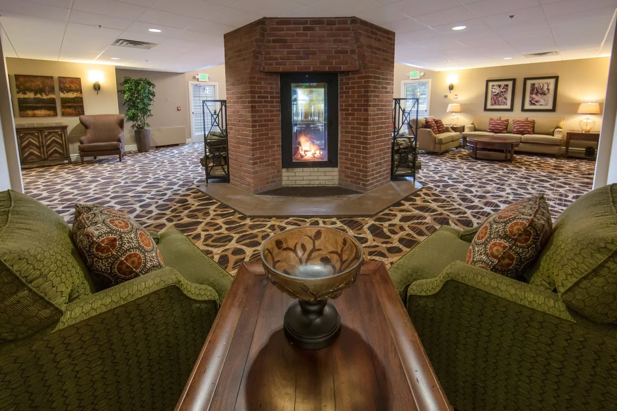 This image captures a central fireplace surrounded by plush seating and a decorative bowl, with an inviting atmosphere that encourages gathering and relaxation. The warm glow of the fire, combined with cozy chairs and thoughtful decor, reflects a comfortable lounge area where guests can unwind after a day outdoors.