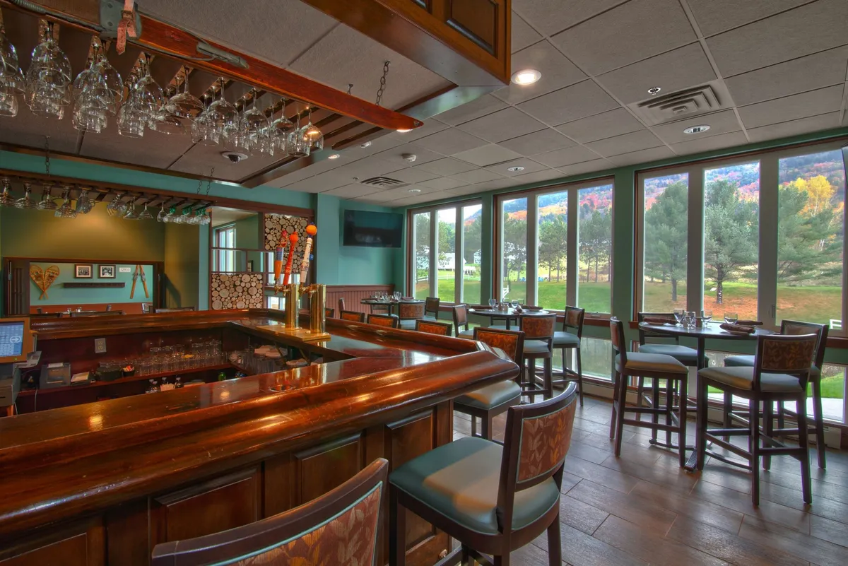 A cozy dining area with a bar counter, ample seating options, large windows letting in natural light, and tasteful decorative wall art. The setting is relaxed yet elegant, ideal for sociable meals or a romantic dinner, and offers a glimpse into on-site dining possibilities.